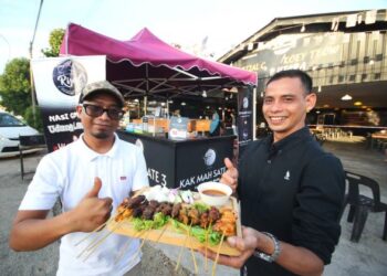 Wan Mohd Hasrul Wan Ahmad (kiri) bersama Pemilik restoran Char Kuey Teow, Nazri Husin menunjukkan pelbagai jenis sate yang dijualnya di Kota Bharu . – UTUSAN/ZULHANIFA SIDEK