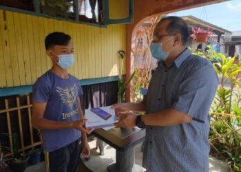 AHMAD Amzad Hashim menyampaikan tablet kepada seorang pelajar di Parlimen Kuala Terengganu bagi melancarkan sesi Pengajaran dan Pembelajaran di Rumah (PdPR)