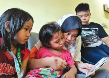 Dari kiri)  Nurmia, Nurnafisha, Nursazzey dan Mohd Irfan melihat gambar kedua ibu bapa mereka di kediaman PPR Taman Sri Keramat, Putatan, Sabah. – UTUSAN/SURAIDAH ROSLAN