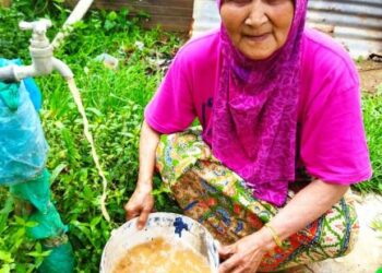 RUBIAH Talib menunjukkan air paip  yang keruh dan berselut di rumahnya di Kampung Tanjung Pari, Baling, baru-baru ini.