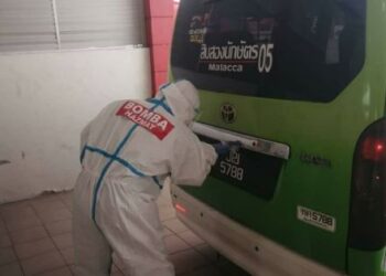 SEORANG anggota Hazmat melakukan kerja-kerja nyahcemar pada kenderaan yang membawa pesakit Covid-19 dari atau ke PKRC MITC, Melaka. - UTUSAN/MUHAMMAD SHAHIZAM TAZALI