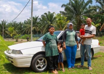 RIZAL Che Majid bersama keluarganya di hadapan kereta yang menjadi tempat berteduh buah mereka selepas dihalau keluar dari rumah yang disewanya.-UTUSAN/MUHAMMAD IZZAT TERMIZIE.