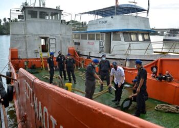 SAHARUDDIN Mohd. Kia (tiga, kanan) melihat getah paip bagi memindahkan minyak diesel dari bot kargo di sebuah stor pelupusan bahan binaan di Kampung Teluk Pasu, Manir di Kuala Terengganu, Terengganu. 
UTUSAN/PUQTRA HAIRRY ROSLI