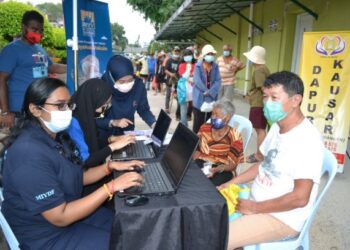 AHLI BNYV membantu gelandangan mendaftar sebagai penerima vaksin menerusi Program Imunisasi Covid-19 Kebangsaan di Pusat Gelandangan Dapur Kausar, Seremban hari ini.-UTUSAN/ZAKKINA WATI AHMAD TARMIZI.