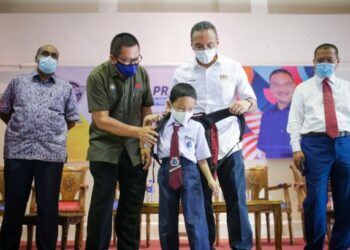 HISHAMMUDDIN Hussein (dua kanan) memakaikan beg sekolah baharu kepada seorang murid pada Program Malaysia Prihatin Parlimen Sembrong di Dewan MPK di Paloh, Johor. -UTUSAN/BAAZLAN IBRAHIM