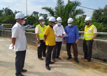 MOHD. Zolkafly Harun (dua dari kanan) mendengar taklimat mengenai kerja baik pulih jalan rebak di Chikus, dekat Teluk Intan hari ini. - UTUSAN