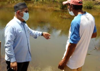 TUAN Ibrahim Tuan Man (kiri) meninjau takungan air bersama penduduk, Wakiman Sarno  sempena Majlis Penyerahan Projek Pertama Wakaf Air Kepada Penduduk Kampung Melayu Seelong, di Senai, Johor. -UTUSAN/ BAAZLAN IBRAHIM