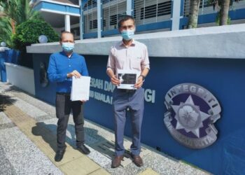 HAMDAN Mohd. Salleh bersama seorang lagi wakil KRAMAT menunjukkan salinan laporan polis di depan IPD Dang Wangi, Kuala Lumpur.