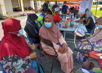 KHADIJAH DIN (tengah) bersama ahli keluarga di pos kawalan pusat operasi mencari suaminya yang jatuh dalam longkang di Chemor, Ipoh hari ini. - UTUSAN/GAMBAR ASLIZA MUSA