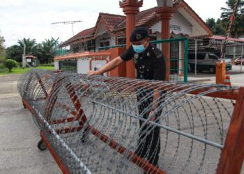 ANGGOTA petugas Penjara Jelebu sedang memasang kawat duri di sekitar pintu utama hadapan Institut Pemulihan Dadah Jabatan Penjara Malaysia Cawangan Jelebu, Negeri Sembilan hari ini.-UTUSAN/MUHAMMAD IZZAT TERMIZIE.