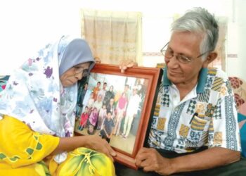 PASANGAN warga emas, Salmah Hashim dan Mohd. Noor Ismail menatap gambar kenangan Hari Raya Aidilfitri  2019 bersama anak, menantu dan cucu di kediaman mereka di Kampung Permatang Pasir, Balik Pulau, Pulau Pinang.