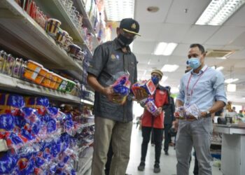 ROSOL Wahid (kiri) memeriksa bekalan roti di sebuah pasar raya di Kuala Terengganu, hari ini.- UTUSAN/PUQTRA HAIRRY ROSLI