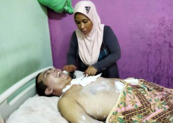 NORMA Che Nai sedang menguruskan anaknya, Izzudin Pathur Radi, yang terlantar akibat kemalangan sejak empat tahun lalu di rumahnya di Kampung Lubuk Kabu, Kuala Pegang, baru-baru ini.