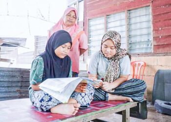 KHAMISAH Mohd. Daud memantau anak-anaknya, Nur Aina Syafina Abdul Rahman Yong (kanan) dan  Nurma Hanum Illias ketika sesi PdPR di Kampung Kuchai, Lambor Kiri, Parit. – UTUSAN /ZULFACHRI ZULKIFLI