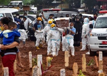 PETUGAS bersiap sedia mengebumikan mayat Covid-19 yang dibawa dengan ambulans dari hospital ke tanah perkuburan di Bekasi, Jawa Barat. -AFP